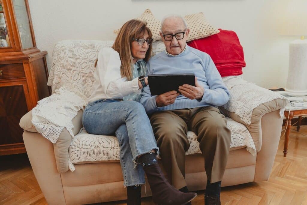 Daughter helping senior father navigate a tablet
